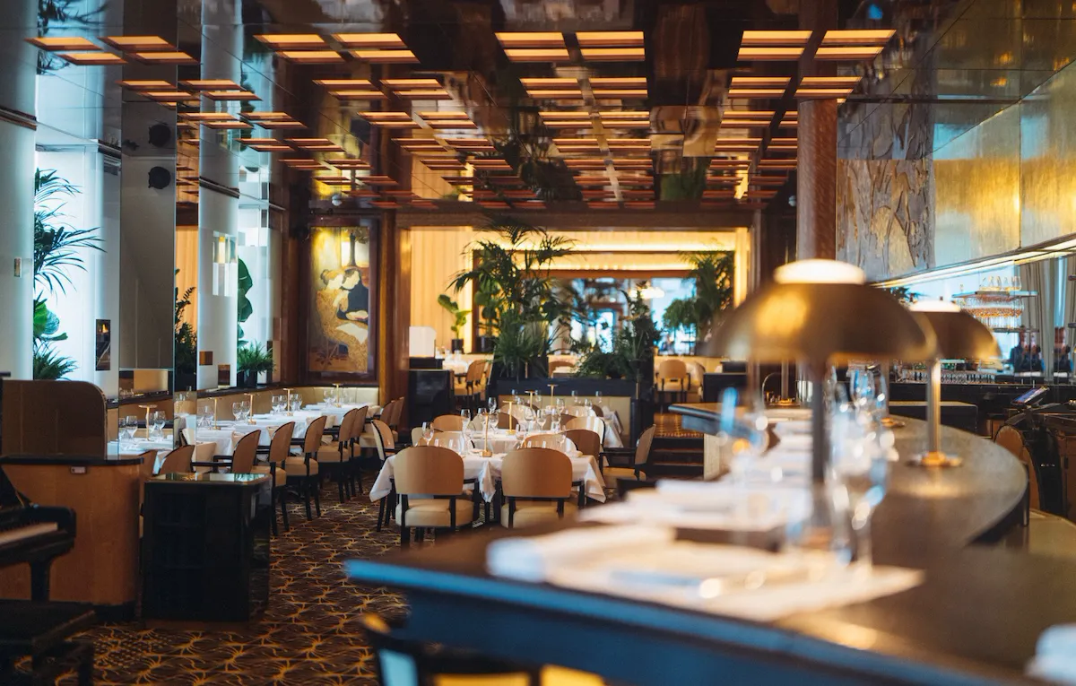 Overview of Le Relais Plaza's dining room lower deck, with the bar at the forefront,at Hotel Plaza Athénée, Paris