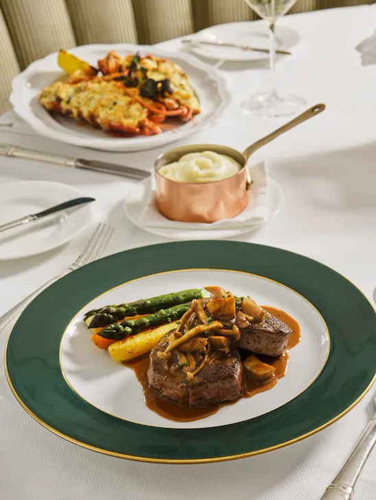 Elegant table setting with plated main course and additional dish in a bright dining room