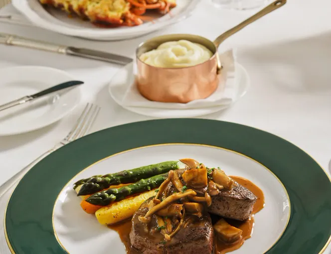 Elegant table setting with plated main course and additional dish in a bright dining room