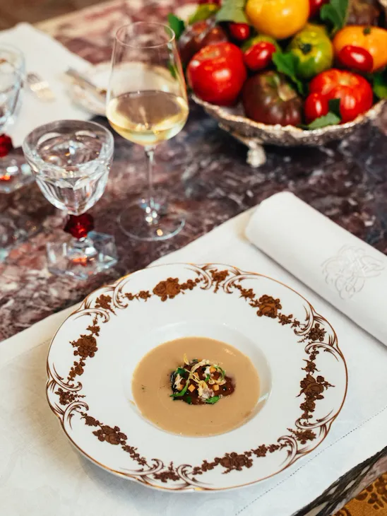Empty plate with food, wine glass, fruit bowl, and napkin on a marble table.