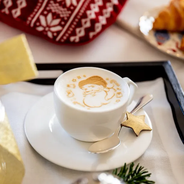 Cappuccino with Santa Claus image and croissants in the background at Hotel Eden, Rome