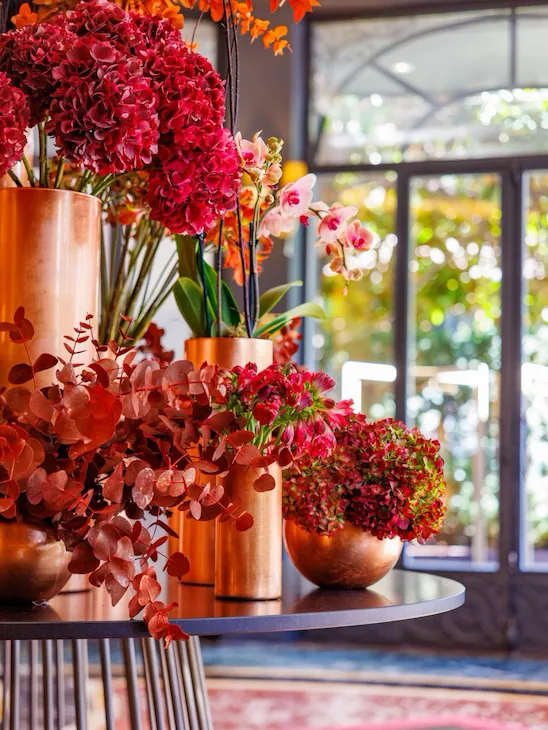 Fiori dai colori sui toni del rosso posizionati sul tavolo tondo all'ingresso