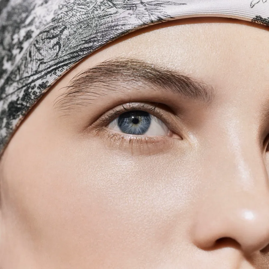 Dior Spa Plaza Athénée's iconography for spa treatments. Here, a female model's nude face with a focus on her bare skin and blue eyes, with a headband.