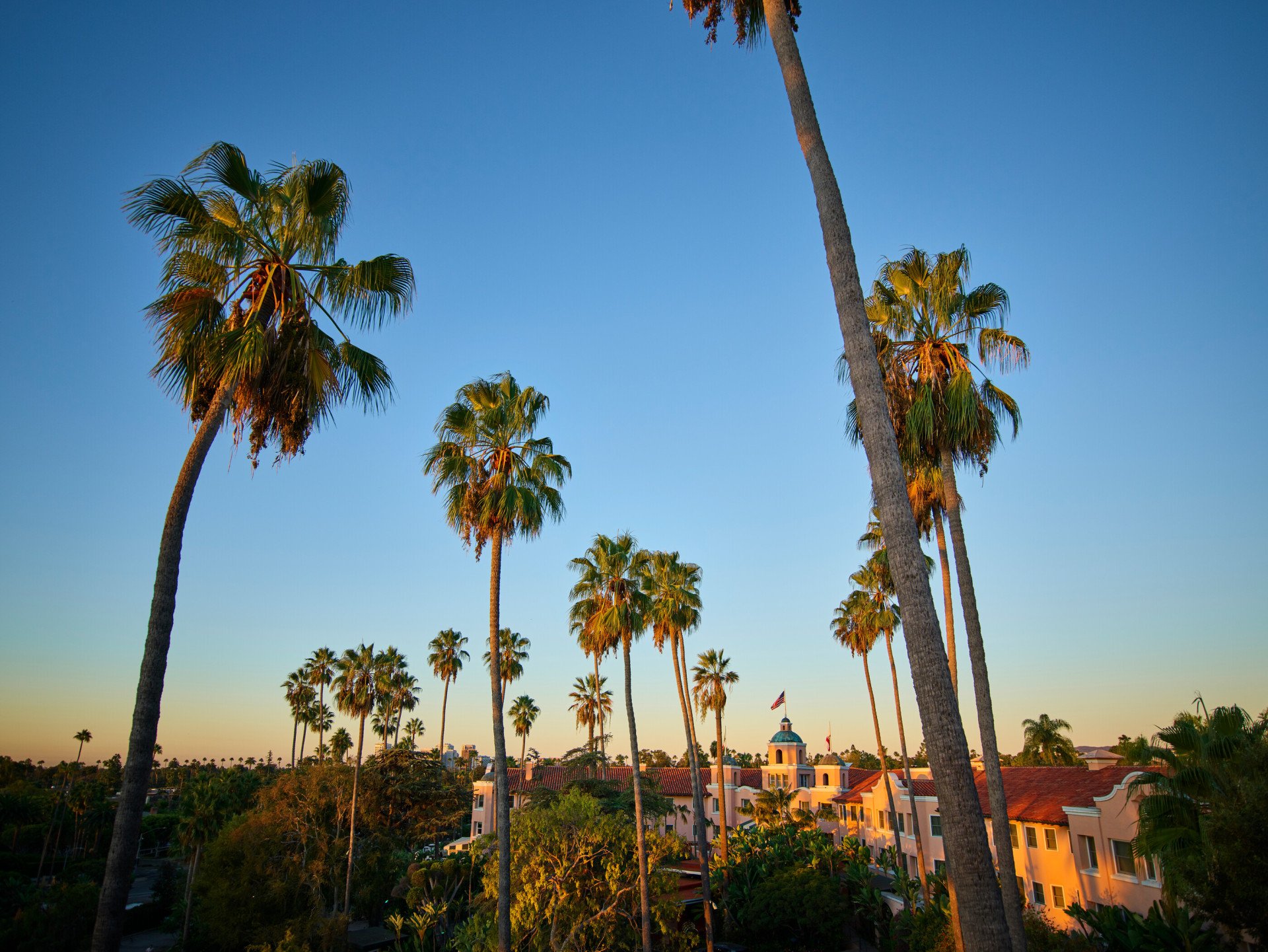 The exterior of The Beverly Hills Hotel with palm trees at sunset, Los Angeles