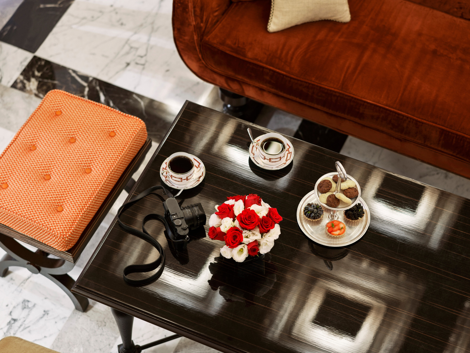 Coffee table with flowers, pastries, two coffee cups and a camera at La Libreria at Hotel Eden, Rome