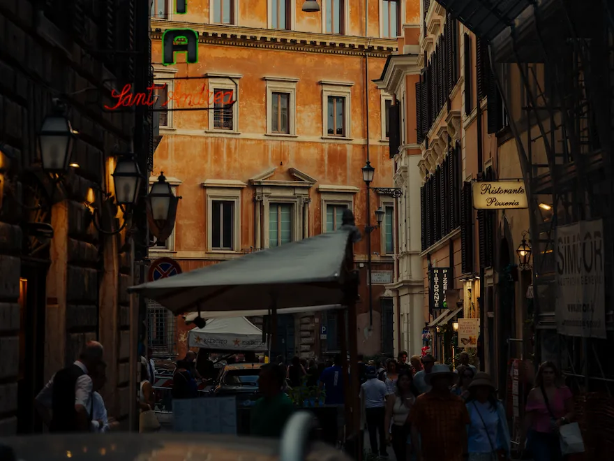 People walk through a busy city alley with signs and buildings, lively and vibrant atmosphere