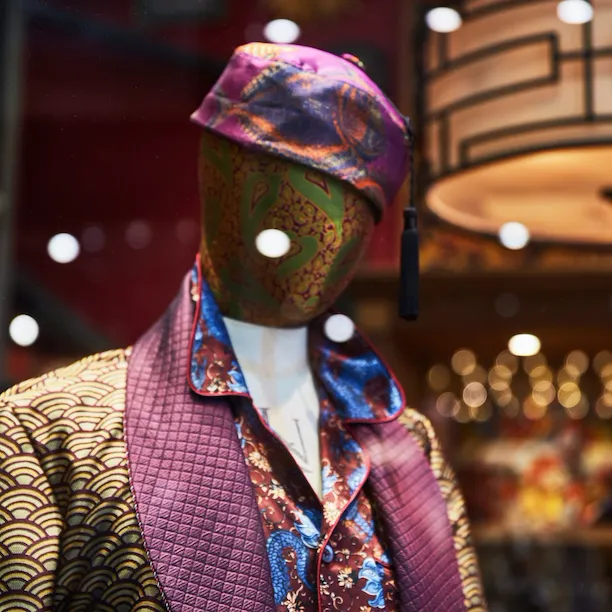 Silk dress coat and hat on mannequin in shop window in Picadilly Arcade, London