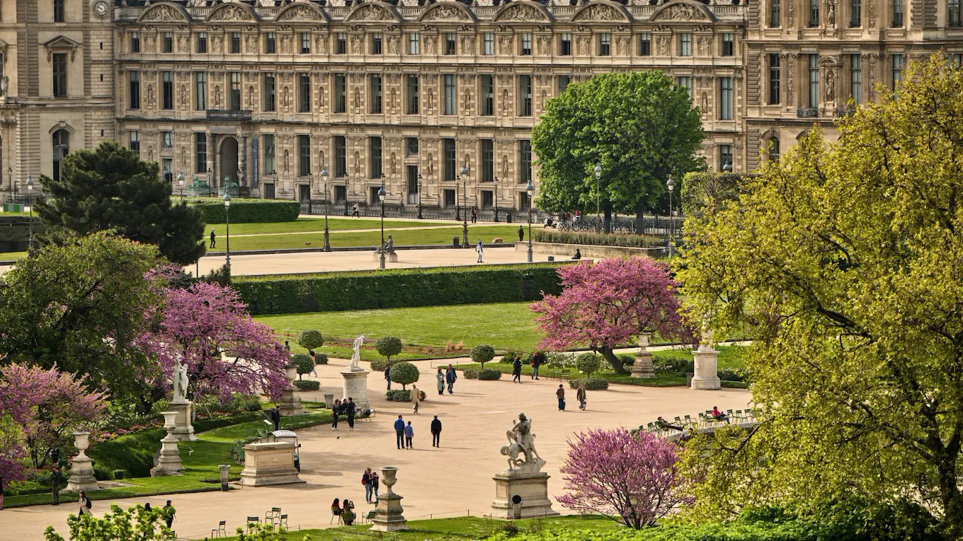 Zoom on the garden of The Louvre with people who are walking inside, at Le Meurice, Paris