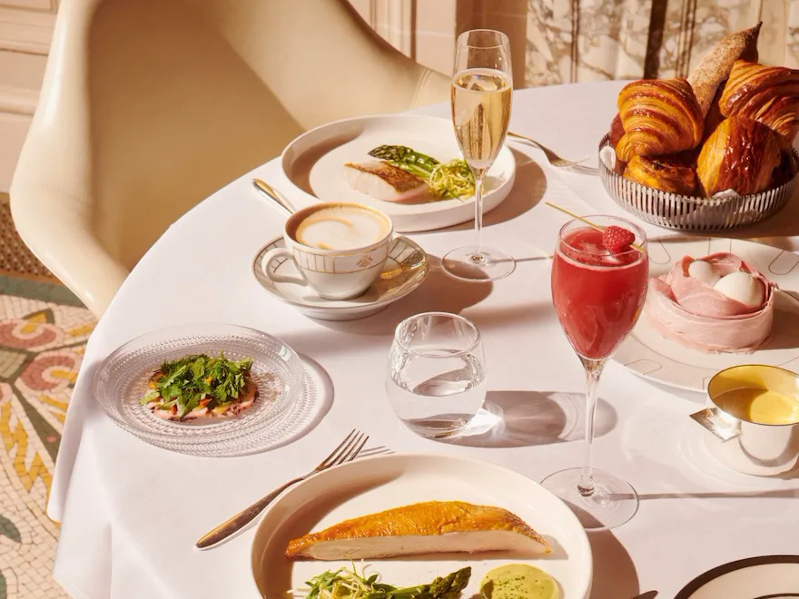 Vue de dessus d'une table de brunch avec poitrine de poulet avec une coupe de champagne, un cocktail et une tasse de café au Meurice, Paris - Dorchester Collection