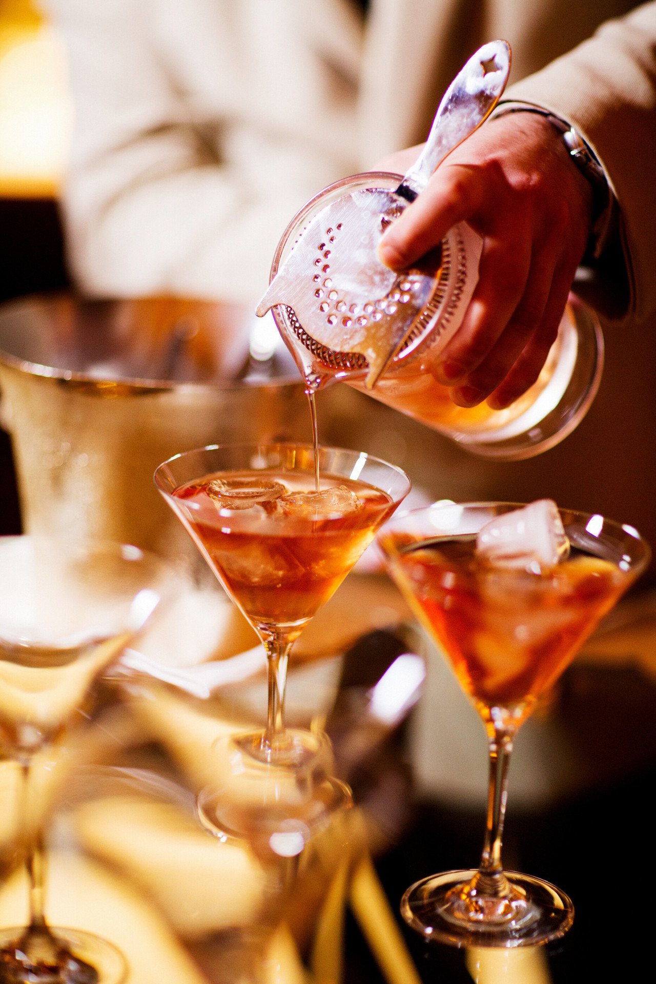 Barman pouring cocktails into Martini glasses at La Libreria at Hotel Eden, Rome