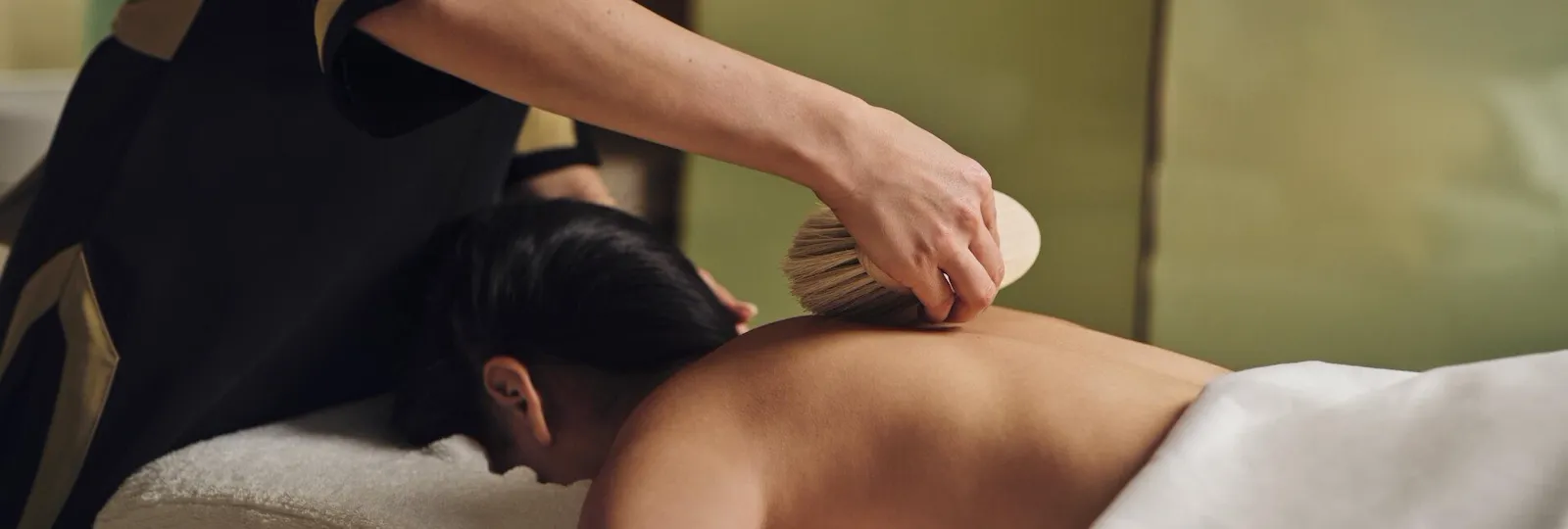 Spa therapist who is actively doing a body treatment with brush