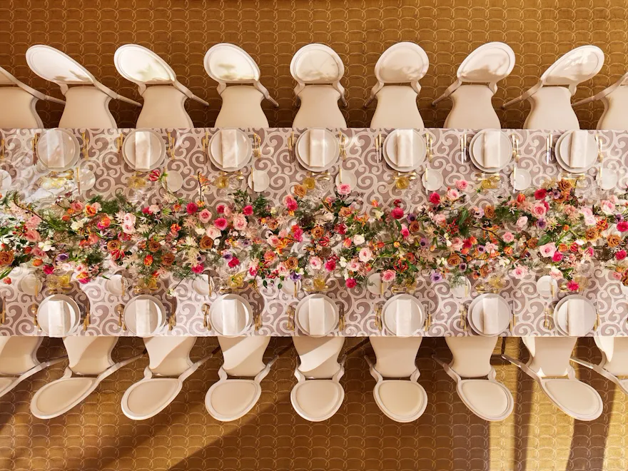 Table captured with white plates, and colorful flower arrangement at Le Salon Organza, Hôtel Plaza Athénée, Paris - Dorchester Collection.