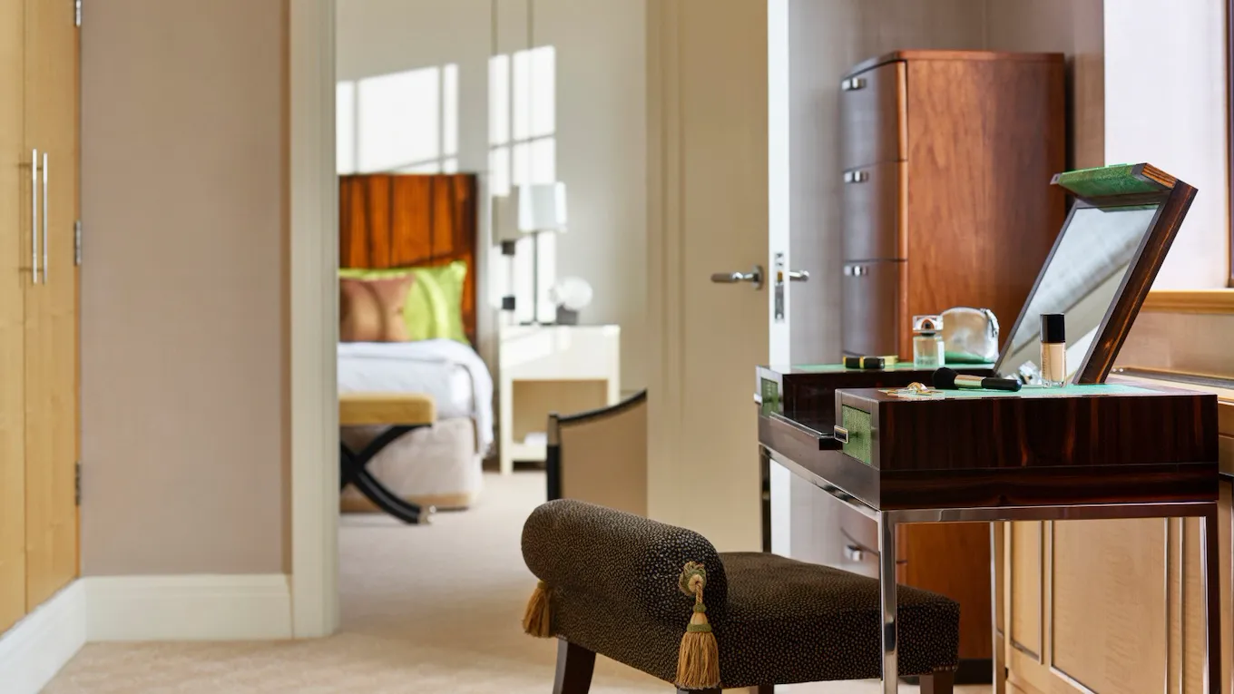 The Harlequin Penthouse Suite vanity table with make up on display and bedroom in background