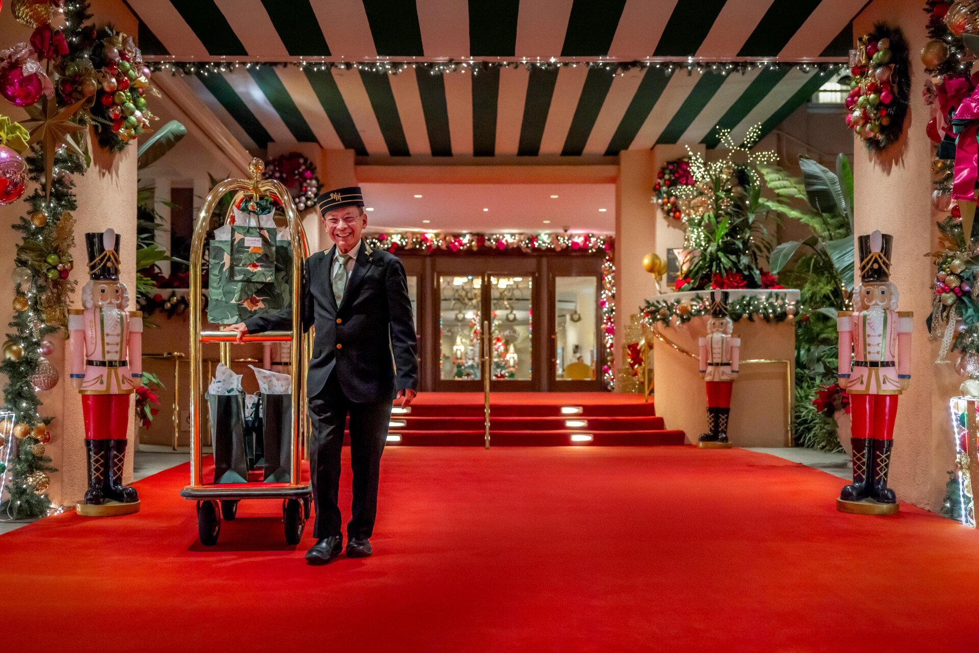 Renato holding a bell cart with gifts on red carpet 