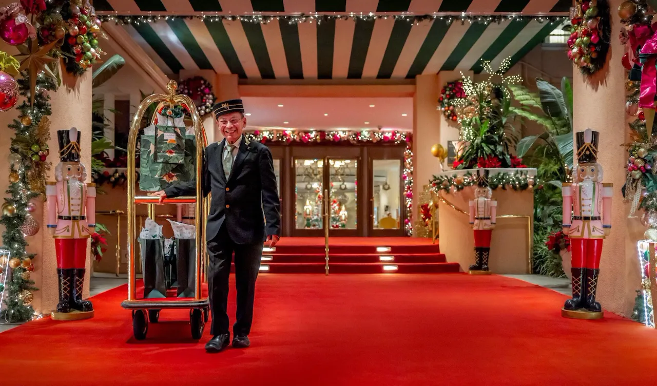 Renato holding a bell cart with gifts on red carpet
