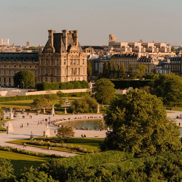 Vue aérienne des jardins des Tuileries avec une lumière jaune lisse, au coucher du soleil. Un étang avec une fontaine et des chaises autour est au centre de l’image, au jardin des Tuileries, Paris