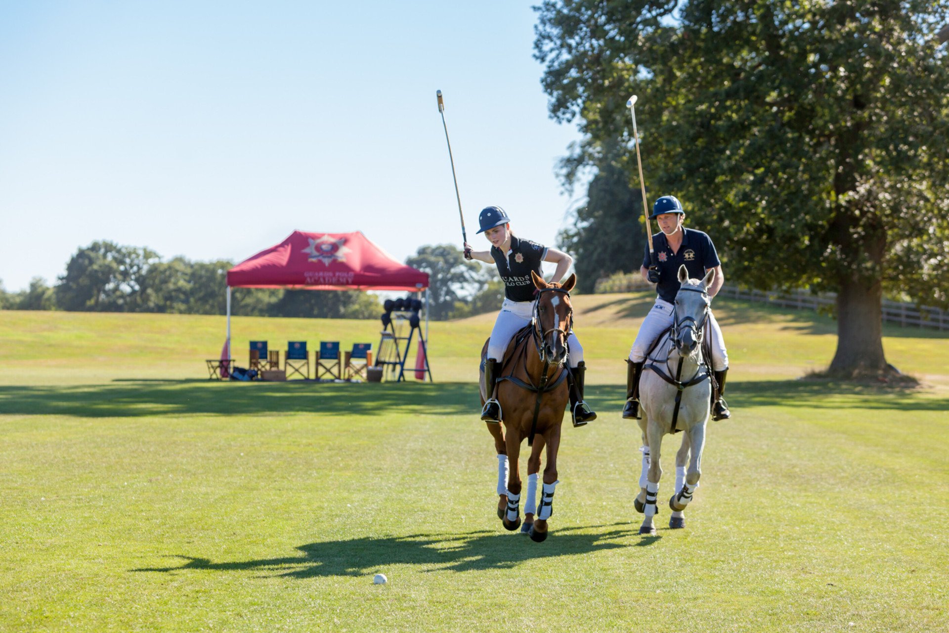 Two people riding horses learning polo at Coworth Park, Ascot