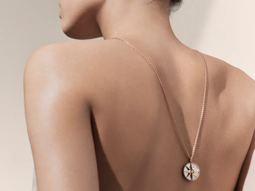 Dior Spa Plaza Athénée's iconography for spa treatments. Here, a light-skin female model seen from the back, with a focus on her long white and gold necklace which hangs on her back.