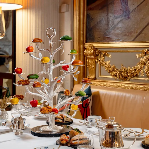 Elegant dining table set with a colorful decorative tree in a luxurious, warmly lit room