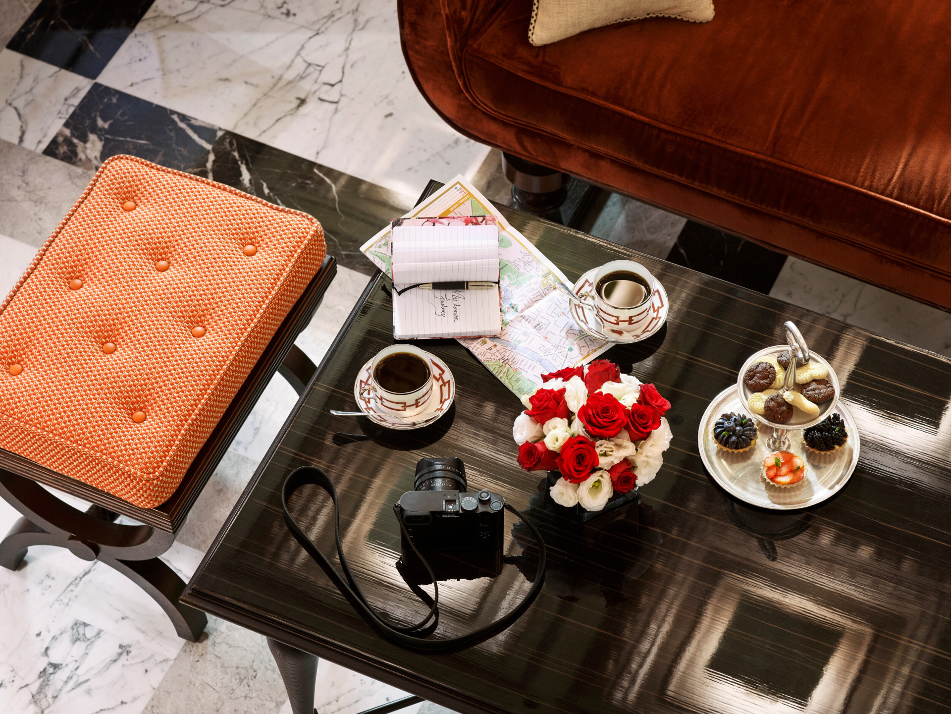 Coffee table with flowers, coffee, selection of pastries, city map and camera at La Libreria at Hotel Eden, Rome