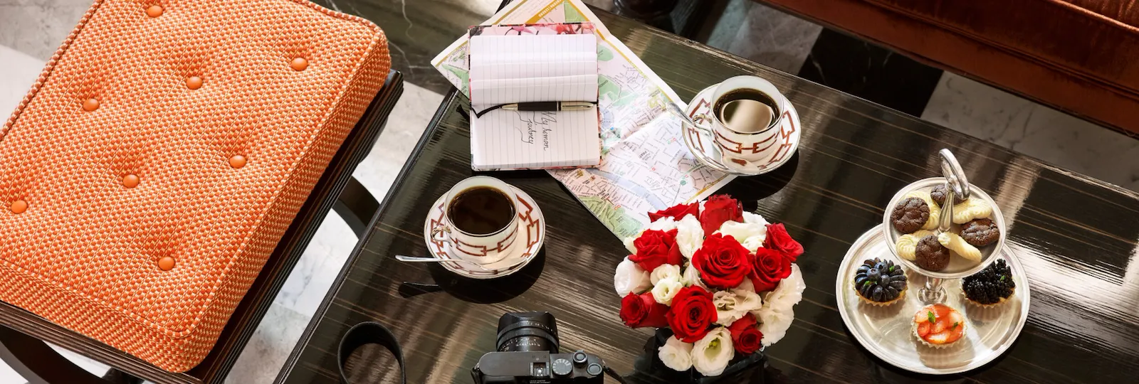 Coffee table with flowers, coffee, selection of pastries, city map and camera at La Libreria at Hotel Eden, Rome