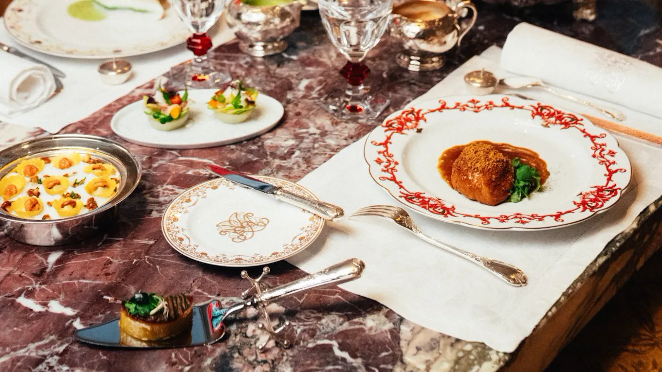 A decorated table with a candelabrum, plates of food, fruits, and glasses in a formal dining setting.