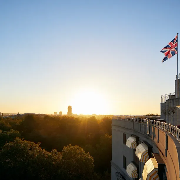 The Union Jack flag flying from the top of The Dorchester overlooking Hyde Park at sunset, London