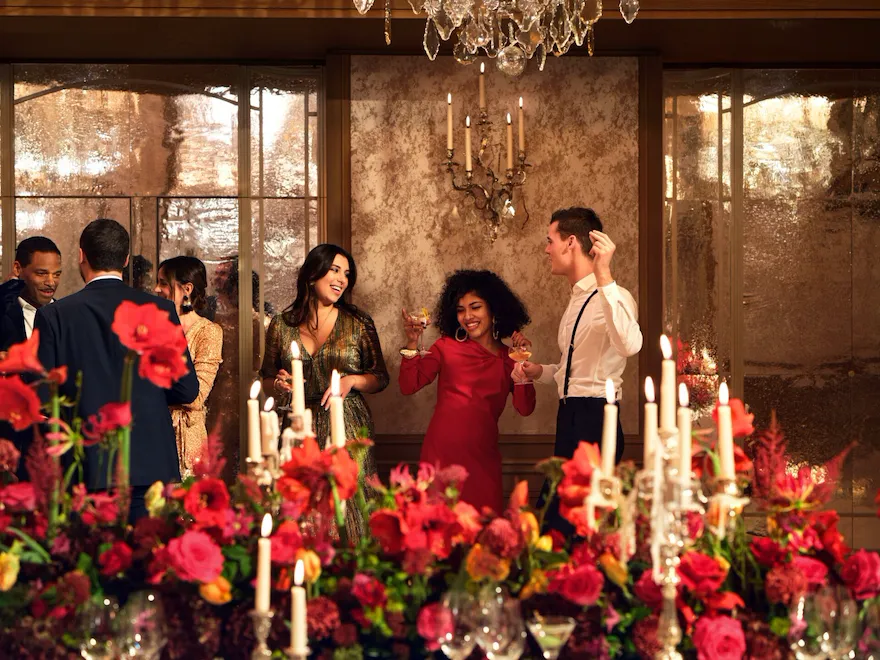 People with red flowers in Le Salon Haute Couture, at Hôtel Plaza Athénée, Paris - Dorchester Collection.