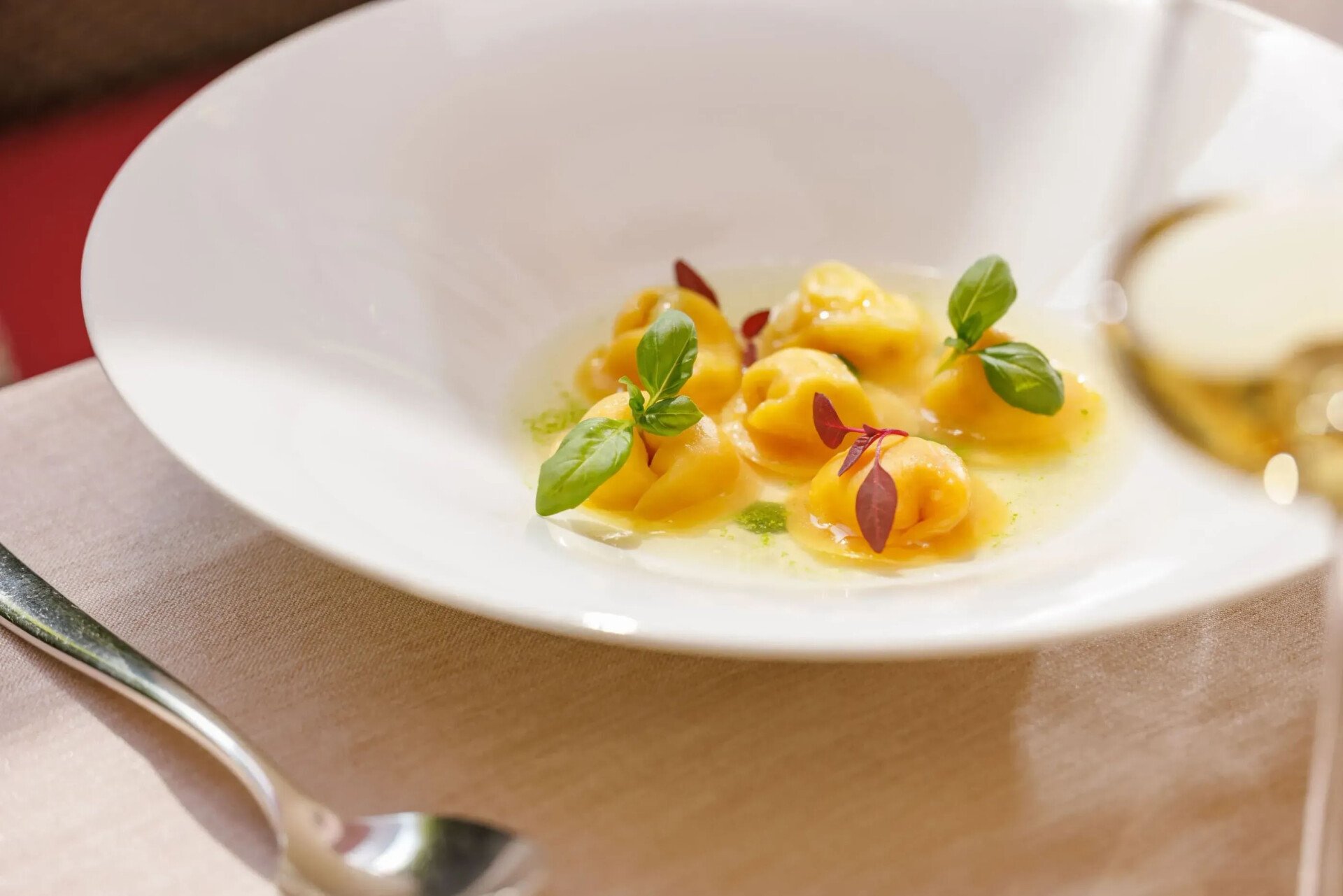 Cappelletti stuffed with burrata and sun-dried tomatoes, warm tomato consommé and basil extract