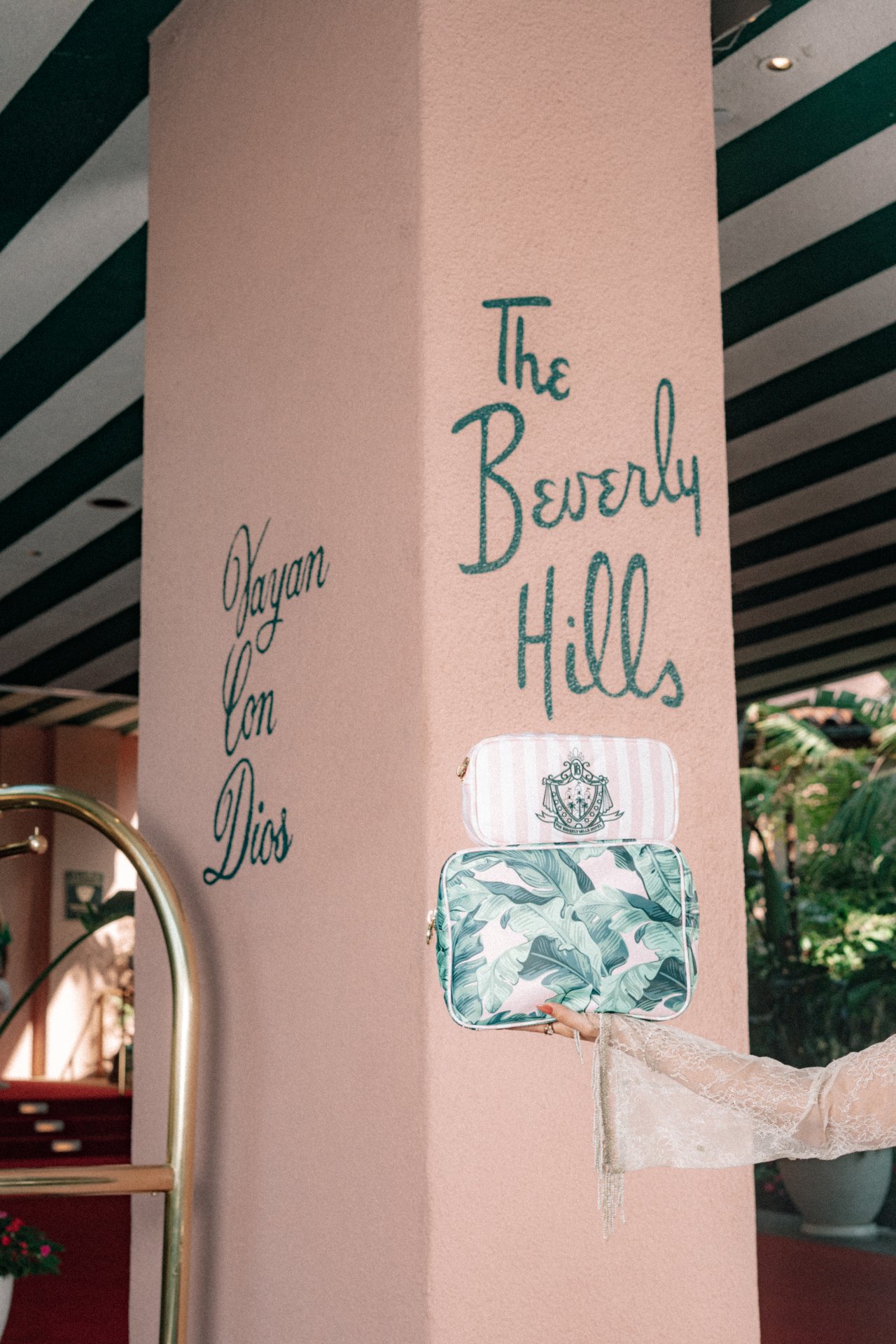A person points to a sign for Beverly Hills on a pillar inside a decorated indoor space.