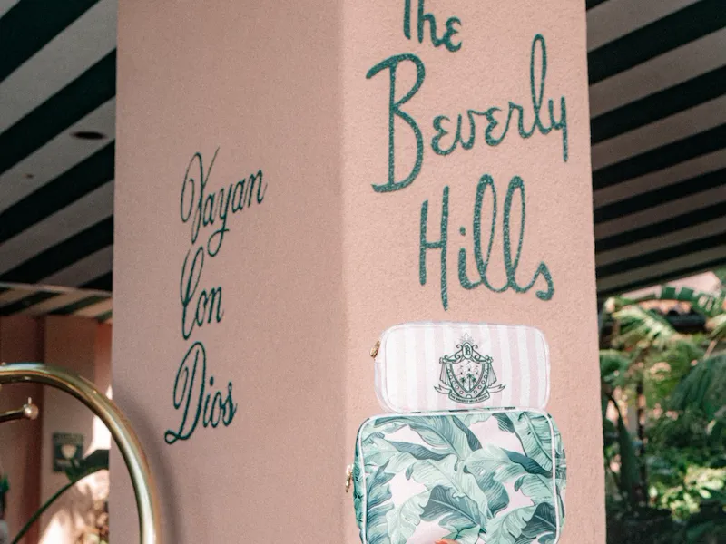 A person points to a sign for Beverly Hills on a pillar inside a decorated indoor space.