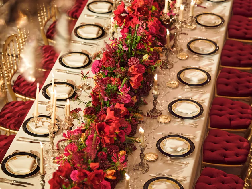 Dîner avec une longue table et des fleurs rouges capturées au Salon Haute Couture, à l’Hôtel Plaza Athénée, Paris - Dorchester Collection.