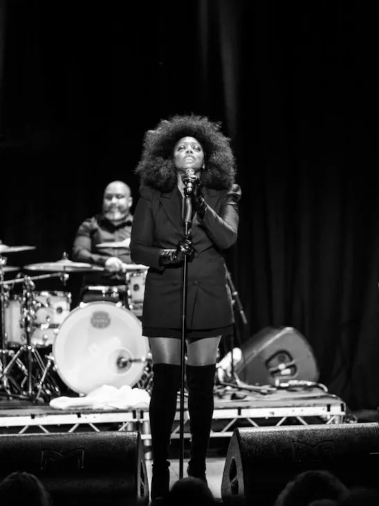 The Dorchester The Promenade Christmas Concert with Mica Paris - Black and white image of singer Mica Paris standing in front of a microphone on stage