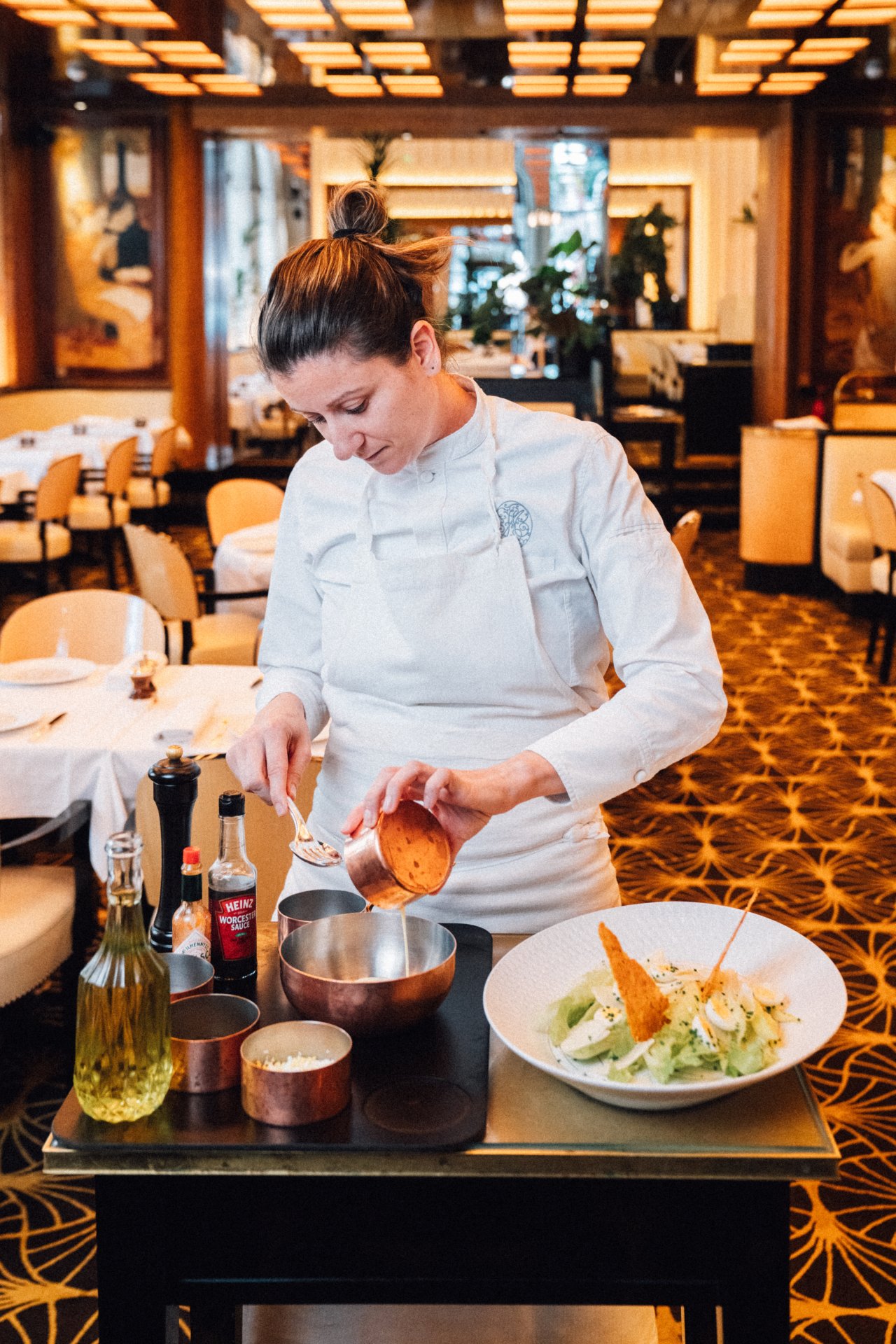 Person in chef's uniform preparing a dish in a restaurant kitchen setting.