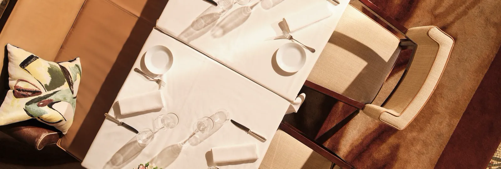 Empty dining table set for a meal, with flower decoration and chairs in a formal dining room