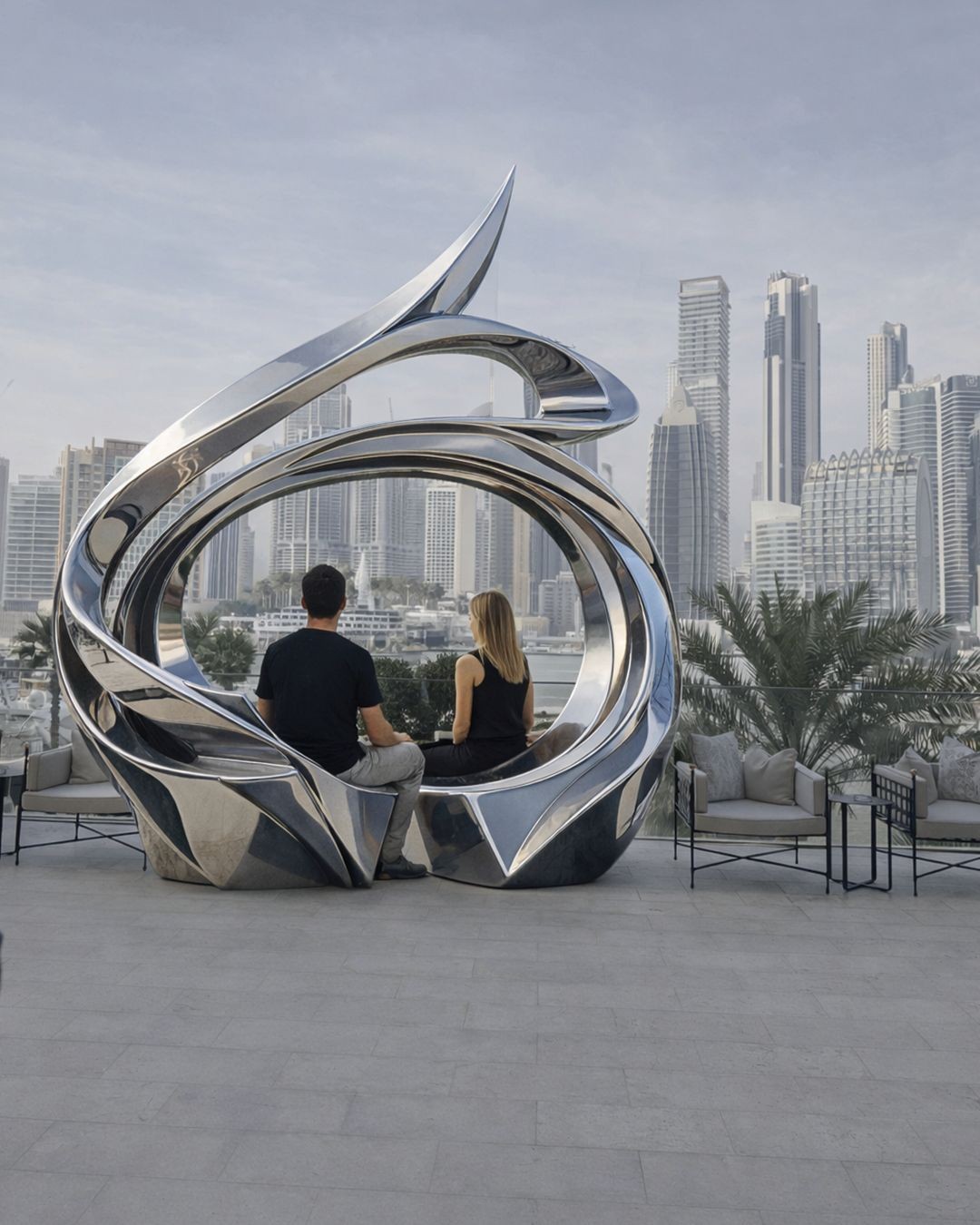 a couple sitting on the JD Malat installation in front of The Lana, enjoying Burj Khalifa