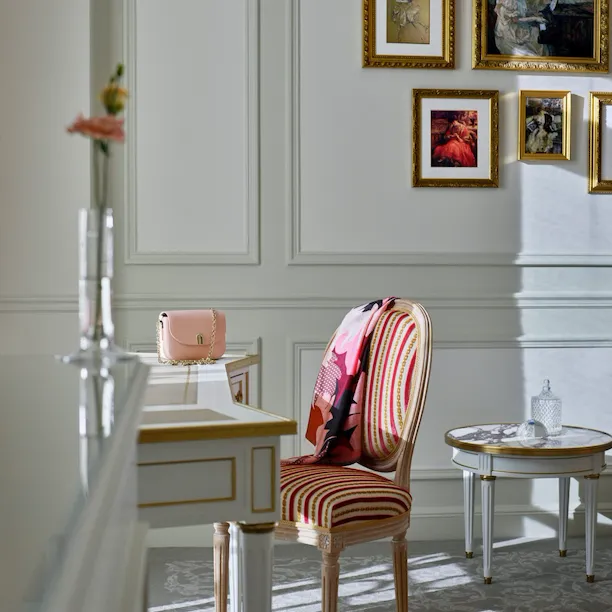 Plan d’un bureau de chambre de luxe avec un sac rose sur le bureau et un foulard sur la chaise. Au Meurice, Paris.