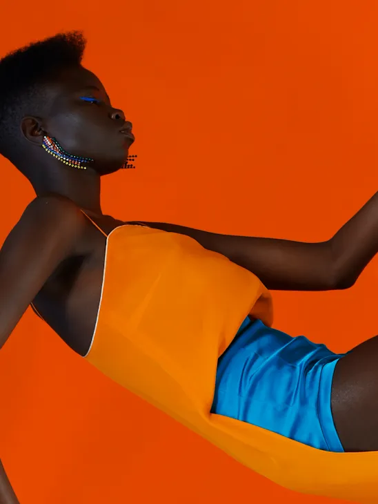Una delle opere del fotografo Zach Gold che ritrae una donna con un top arancione e degli shorts blu elettrico su sfondo arancione.