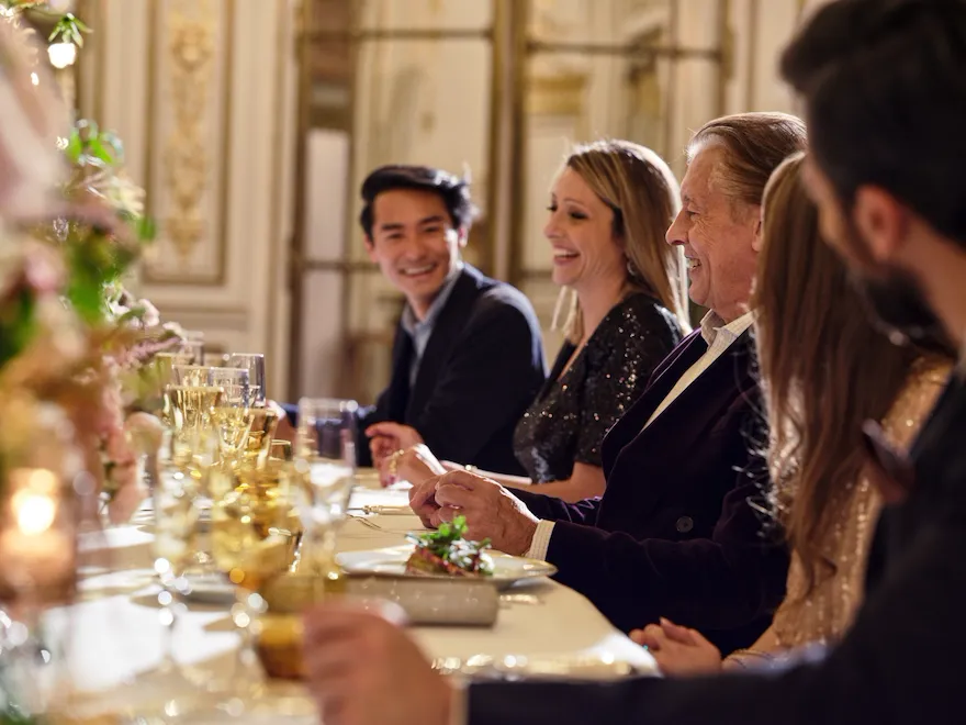 People laughing at the table during a dinner in Le Salon Pompadour at Le Meurice, Paris - Dorchester Collection