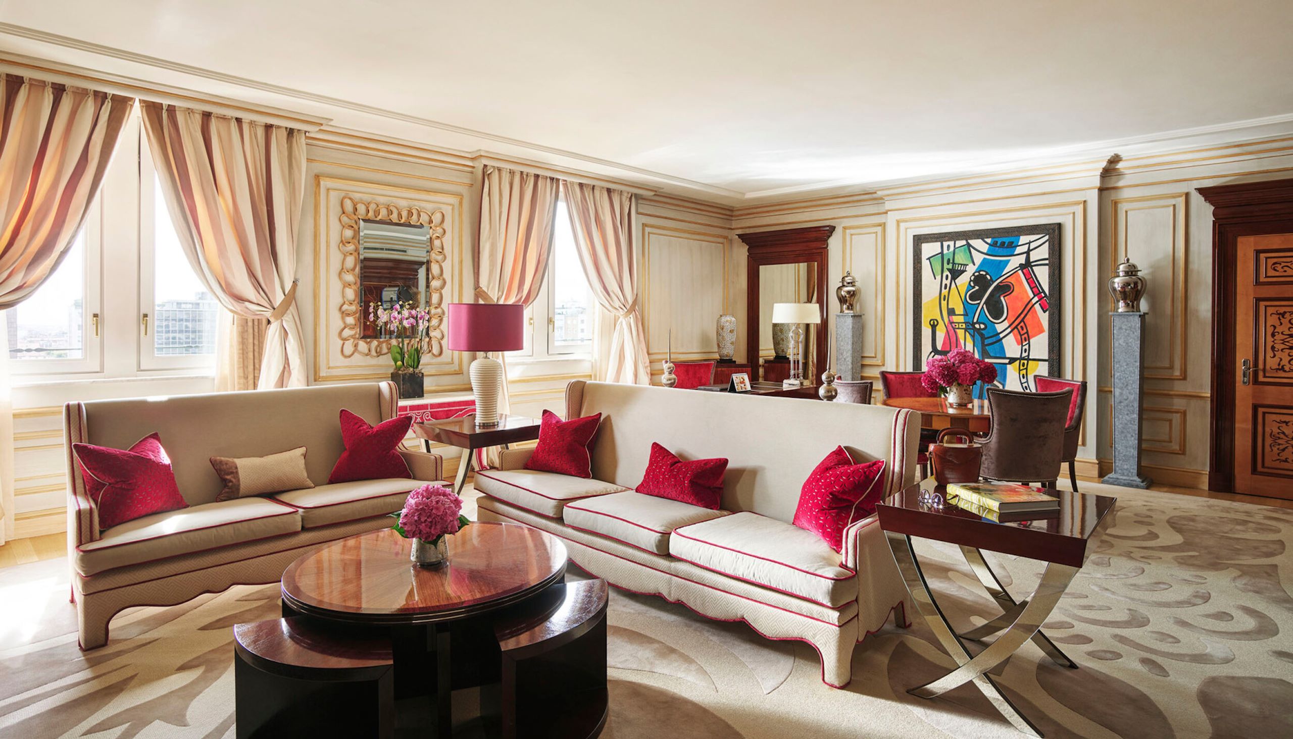 Imperial Executive Suite Living Room furnished with white sofas in the foreground and colourful art pieces in the background 