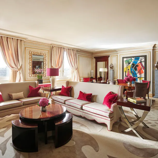 Imperial Executive Suite Living Room furnished with white sofas in the foreground and colourful art pieces in the background