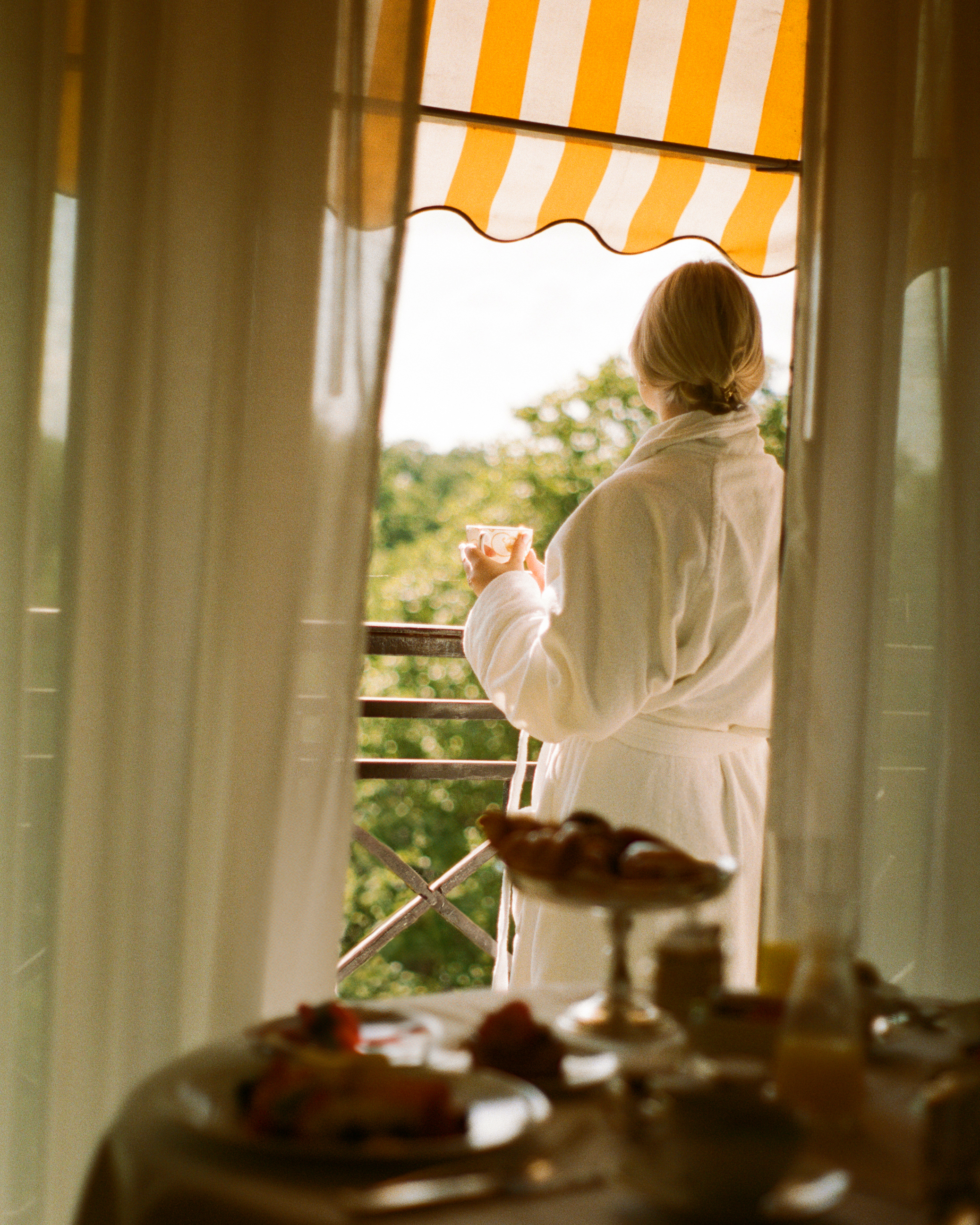Woman on balcony looking out over the park in a robe