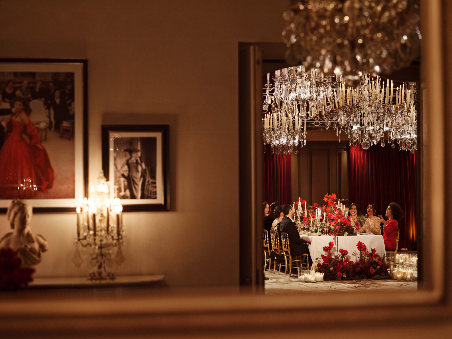 Dinner set up with a long table and red flowers captured in Le Salon Haute Couture, at Hôtel Plaza Athénée, Paris - Dorchester Collection.