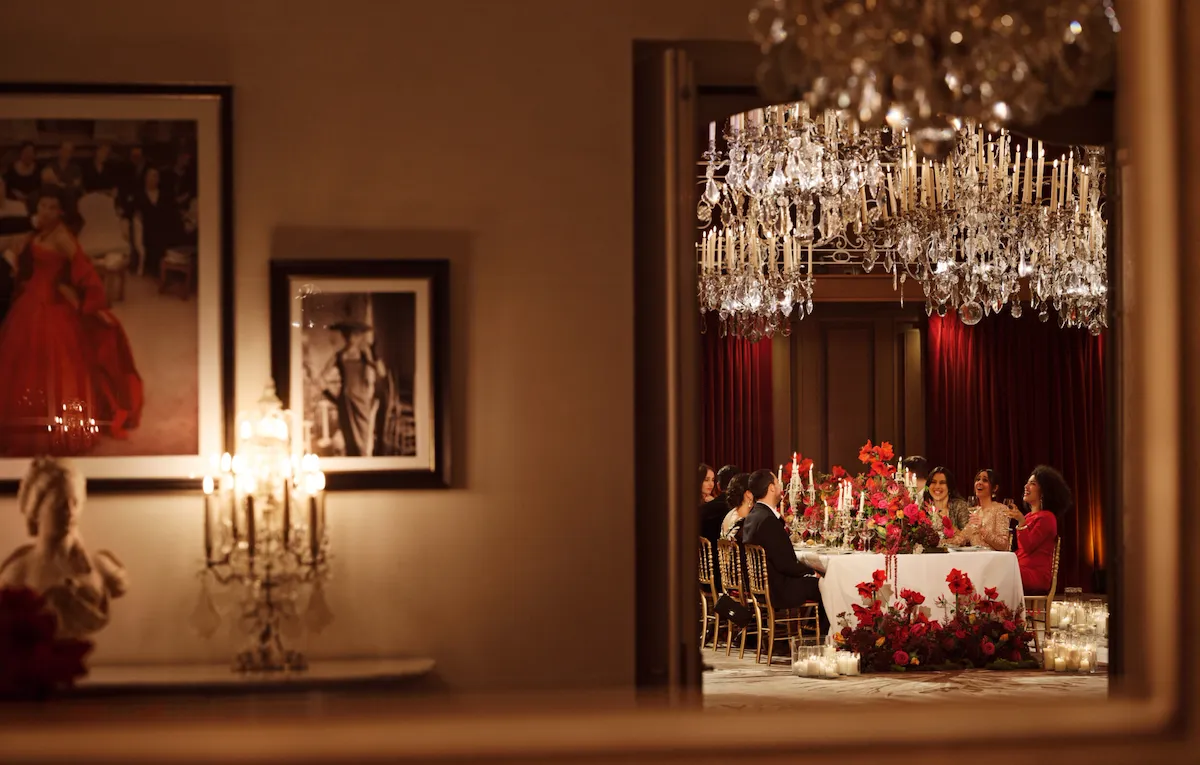 Dinner set up with a long table and red flowers captured in Le Salon Haute Couture, at Hôtel Plaza Athénée, Paris - Dorchester Collection.