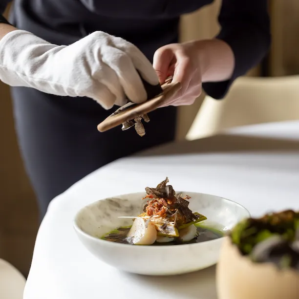 Hand grating truffle over scallops with leek, eel and sausage at Restaurant Le Meurice Alain Ducasse, at Le Meurice, Paris.