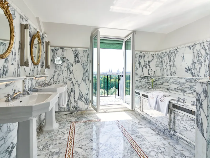 Bright marble bathroom with a balcony view, elegant mirrors, and a relaxing atmosphere