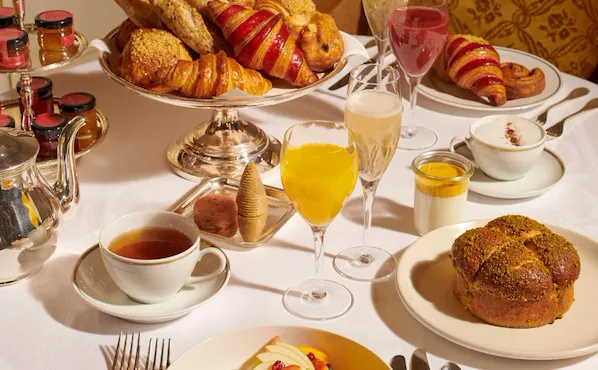 Images du brunch au Jean Imbert au Plaza Athénée. Avec du pain, des salades, des œufs et des pâtisseries affichés sur la table ainsi que des jus et du champagne sous un angle rapproché