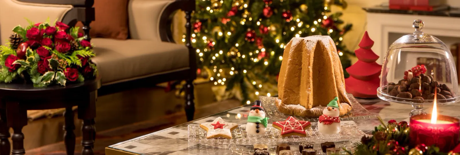 Suite decorata con albero di Natale, composizioni natalizie e un pandaro con dolcetti su di un tavolo da salotto