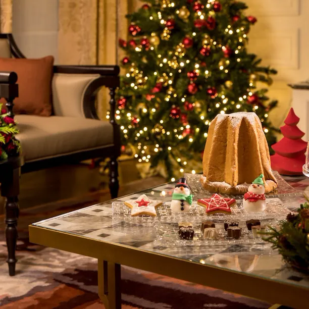 Suite decorata con albero di Natale, composizioni natalizie e un pandaro con dolcetti su di un tavolo da salotto